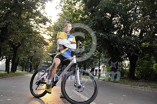 Fit happy young man smiling on mountain bike in park Fit happy young man smiling on mountain bike in park