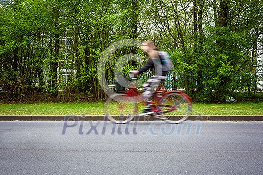 Motion blurred female biker on a city street, going fast Motion blurred female biker on a city street, going fast