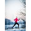 Winter running - Young woman running outdoors on a cold winter day (motion blurred image, color toned image)