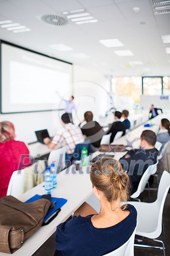 People listening to a presentation in a modern, bright meeting room (shallow DOF; color toned image)