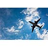 Dark silhouette of an airplane flying over the blue skies