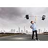 Cute boy of school age lifting barbell above head