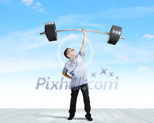 Cute boy of school age lifting barbell above head Cute boy of school age lifting barbell above head