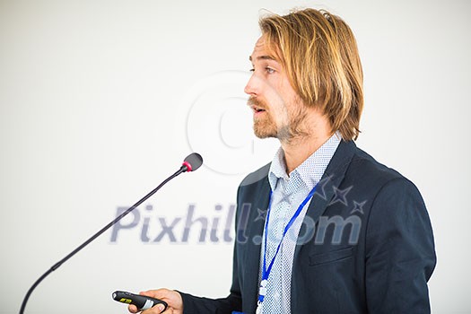 Handsome young man giving a speech at a conference Handsome young man giving a speech at a conference