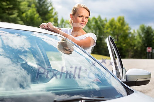 Young, attractive, happy woman standing by her car, being a proud owner of her new vehicle Young, attractive, happy woman standing by her car, being a proud owner of her new vehicle