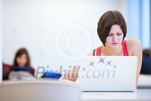 Pretty, young college student studying in the library/a study room at campus , using her modern laptop computer, writing notes, preparing for exams (shallow DOF) Pretty, young college student studying in the library/a study room at campus , using her modern laptop computer, writing notes, preparing for exams (shallow DOF)