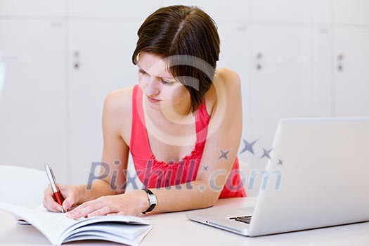 Pretty, young college student studying in the library/a study room at campus , using her modern laptop computer, writing notes, preparing for exams (shallow DOF) Pretty, young college student studying in the library/a study room at campus , using her modern laptop computer, writing notes, preparing for exams (shallow DOF)