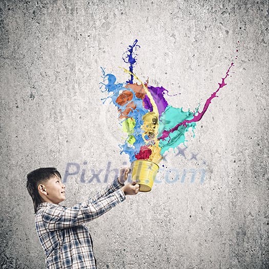 Cute boy splashing colorful paint from bucket Cute boy splashing colorful paint from bucket