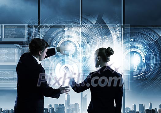 Rear view of businessman and businesswoman touching icon of digital screen Rear view of businessman and businesswoman touching icon of digital screen
