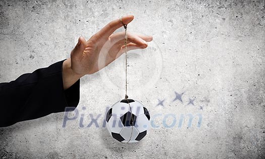 Close up of male hand holding football ball on rope Close up of male hand holding football ball on rope
