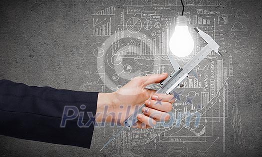 Close up of business person hand measuring bulb Close up of business person hand measuring bulb