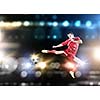 Young football player on stadium kicking ball