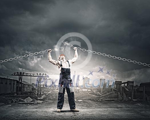 Strong man in uniform tearing metal chain with hands Strong man in uniform tearing metal chain with hands