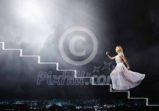 Young woman in white long dress walking up the staircase Young woman in white long dress walking up the staircase