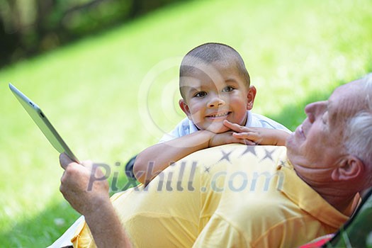 grandfather and child in park using tablet computer grandfather and child in park using tablet computer