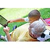 grandfather and child in park using tablet computer