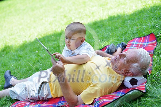 grandfather and child in park using tablet computer grandfather and child in park using tablet computer