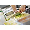 Handsome chef dressed in white uniform decorating pasta salad and seafood fish in modern kitchen
