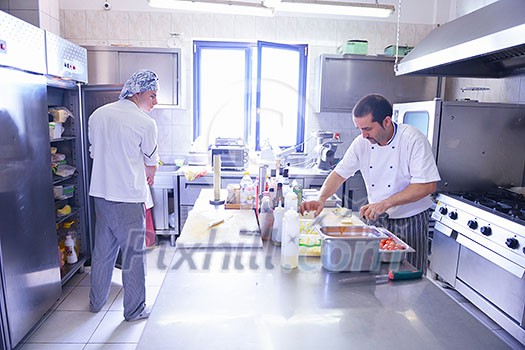 Handsome chef dressed in white uniform decorating pasta salad and seafood fish in modern kitchen Handsome chef dressed in white uniform decorating pasta salad and seafood fish in modern kitchen