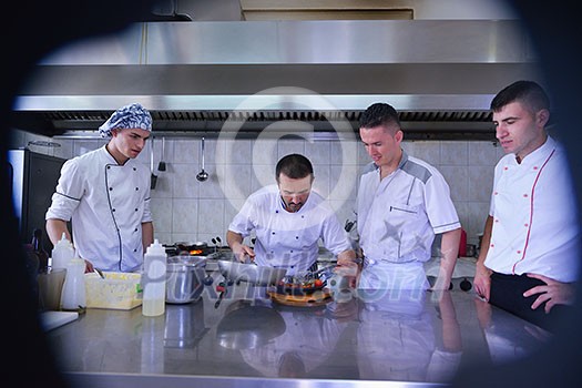 Handsome chef dressed in white uniform decorating pasta salad and seafood fish in modern kitchen Handsome chef dressed in white uniform decorating pasta salad and seafood fish in modern kitchen