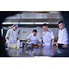 Handsome chef dressed in white uniform decorating pasta salad and seafood fish in modern kitchen
