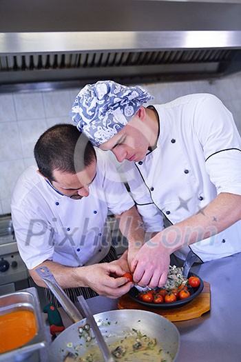 Handsome chef dressed in white uniform decorating pasta salad and seafood fish in modern kitchen Handsome chef dressed in white uniform decorating pasta salad and seafood fish in modern kitchen