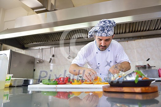 Handsome chef dressed in white uniform decorating pasta salad and seafood fish in modern kitchen Handsome chef dressed in white uniform decorating pasta salad and seafood fish in modern kitchen