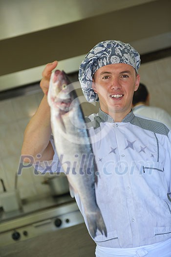 Handsome chef dressed in white uniform decorating pasta salad and seafood fish in modern kitchen Handsome chef dressed in white uniform decorating pasta salad and seafood fish in modern kitchen