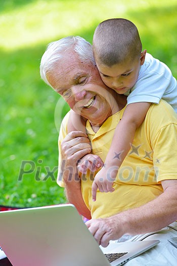 happy elderly senior grandfather and child in park using laptop computer happy elderly senior grandfather and child in park using laptop computer