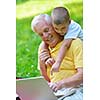 happy elderly senior grandfather and child in park using laptop computer