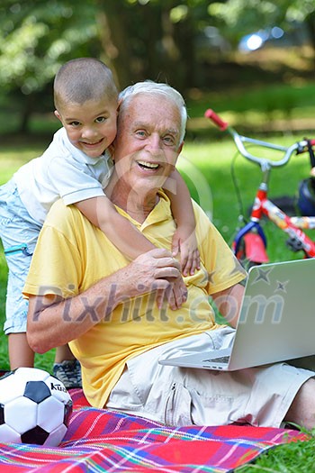 happy elderly senior grandfather and child in park using laptop computer happy elderly senior grandfather and child in park using laptop computer