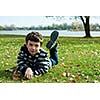 Cute boy  in autumn park laying on grass 