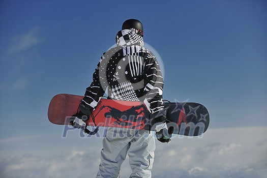 snowboarder relaxing and posing at sunny day on winter season with blue sky in background snowboarder relaxing and posing at sunny day on winter season with blue sky in background