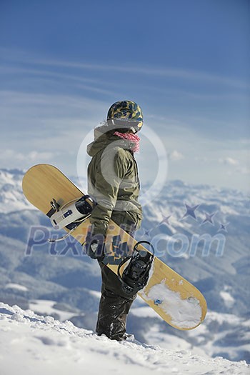 snowboarder relaxing and posing at sunny day on winter season with blue sky in background snowboarder relaxing and posing at sunny day on winter season with blue sky in background