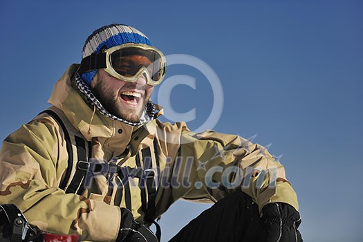 snowboarder relaxing and posing at sunny day on winter season with blue sky in background snowboarder relaxing and posing at sunny day on winter season with blue sky in background