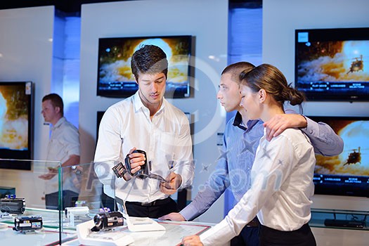people in consumer electronics retail store looking at latest laptop, television and photo camera to buy people in consumer electronics retail store looking at latest laptop, television and photo camera to buy