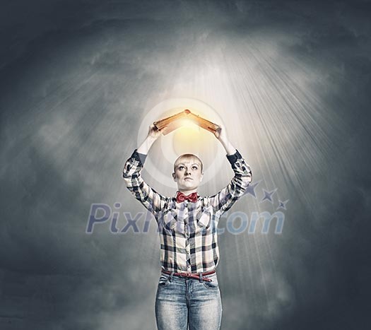 Young woman in shirt holding book above head Young woman in shirt holding book above head