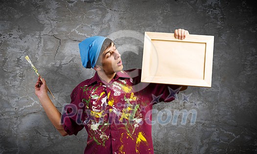 Young handsome man painter with brush in hand Young handsome man painter with brush in hand