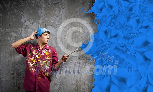 Young handsome man painter with brush in hand Young handsome man painter with brush in hand