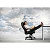 Young businesswoman sitting in chair with legs on table and reading book