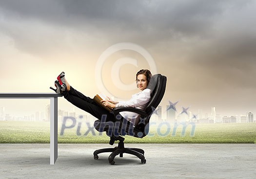 Young businesswoman sitting in chair with legs on table and reading book Young businesswoman sitting in chair with legs on table and reading book