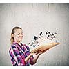 Young woman in casual holding opened book with icons flying out