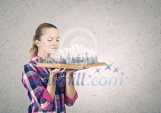 Young woman in casual holding opened book with city model Young woman in casual holding opened book with city model