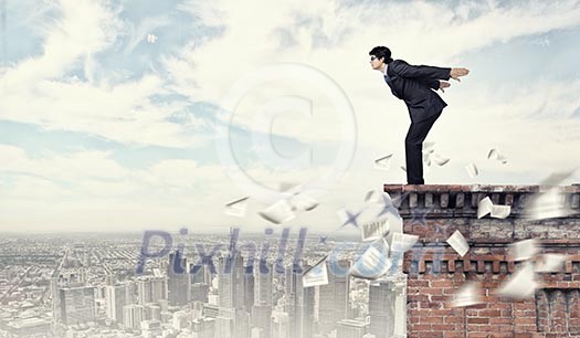 Image of young businessman in goggles jumping from top of building Image of young businessman in goggles jumping from top of building
