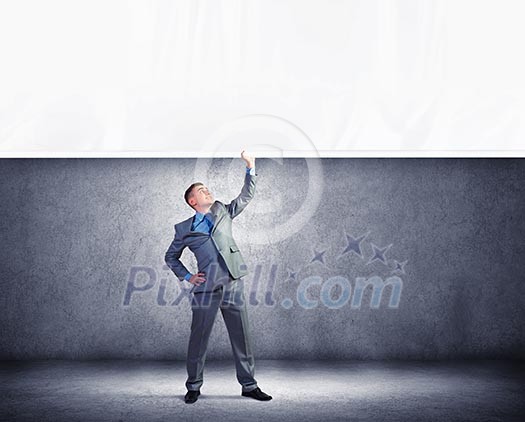 Image of young businessman pulling blank banner from above Image of young businessman pulling blank banner from above