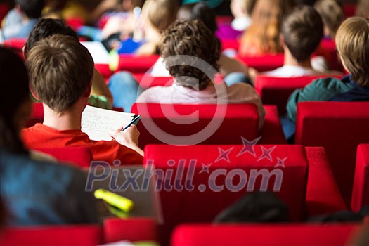 University students sitting in class, taking notes University students sitting in class, taking notes