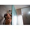 Young woman washing her hair with shampoo, taking a hot long shower