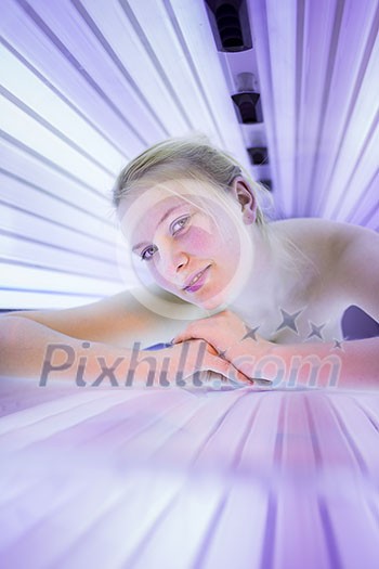 Pretty, young woman tanning her skin in a modern solarium/sunbed. Getting an energy boost during dark winter days. Pretty, young woman tanning her skin in a modern solarium/sunbed. Getting an energy boost during dark winter days.
