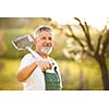 Portrait of a handsome senior man gardening in his garden, on a lovely spring day (color toned image)