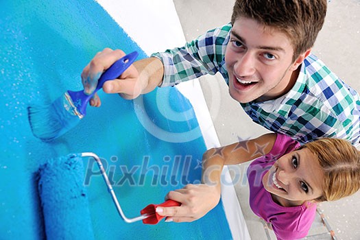 happy young couple paint in green and blue color white wall of their new home happy young couple paint in green and blue color white wall of their new home